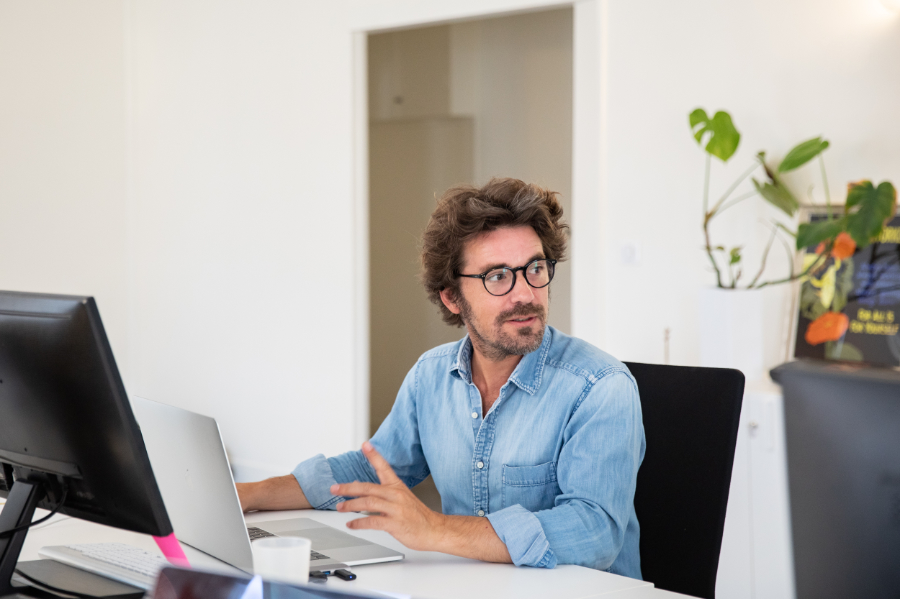 Bertrand Behaghel is sitting at his desk talking to a person