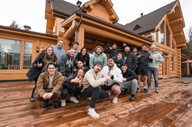 The team posing together in front of a chalet during a company retreat